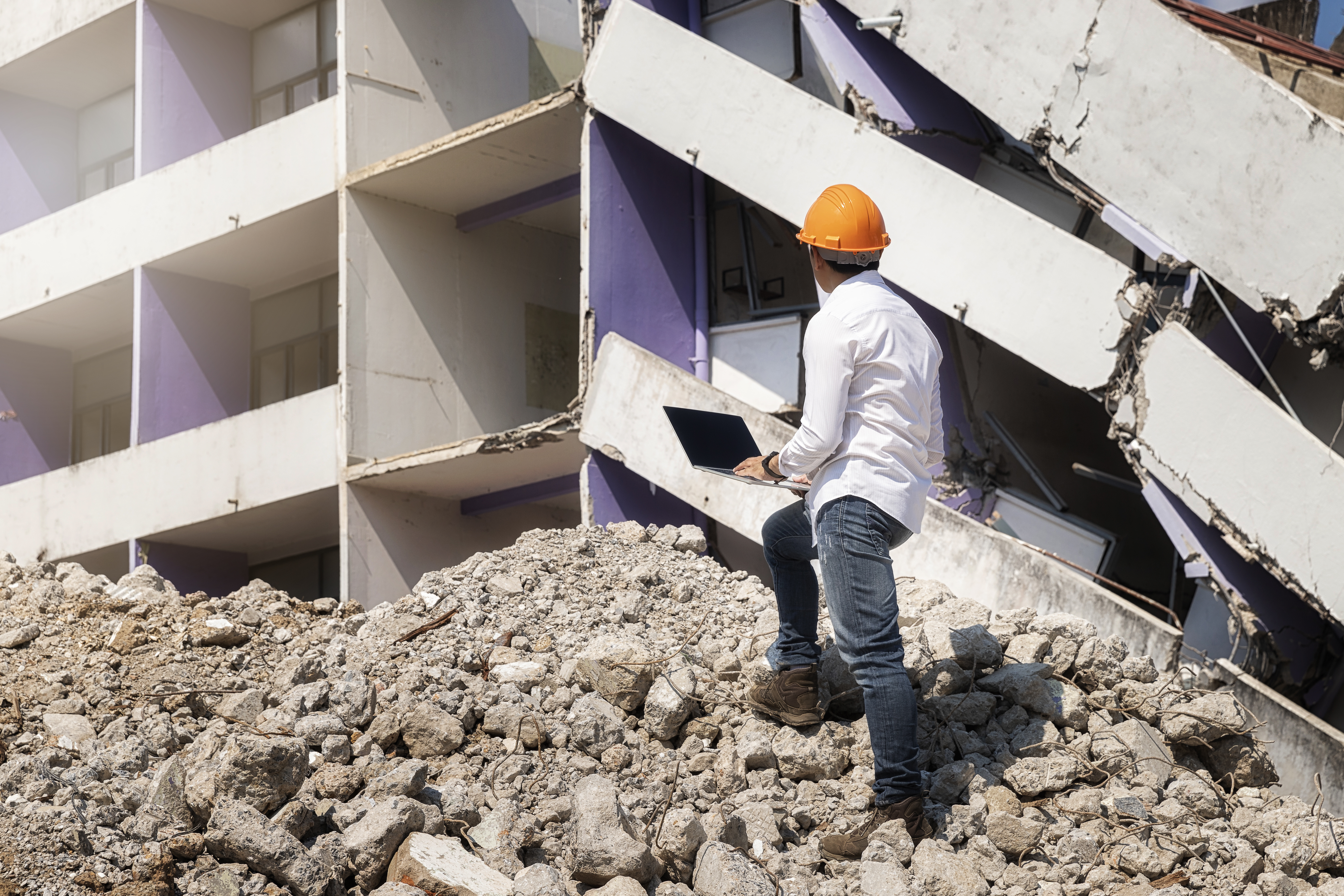 Engineer holding laptop is checking for destruction, demolishing building